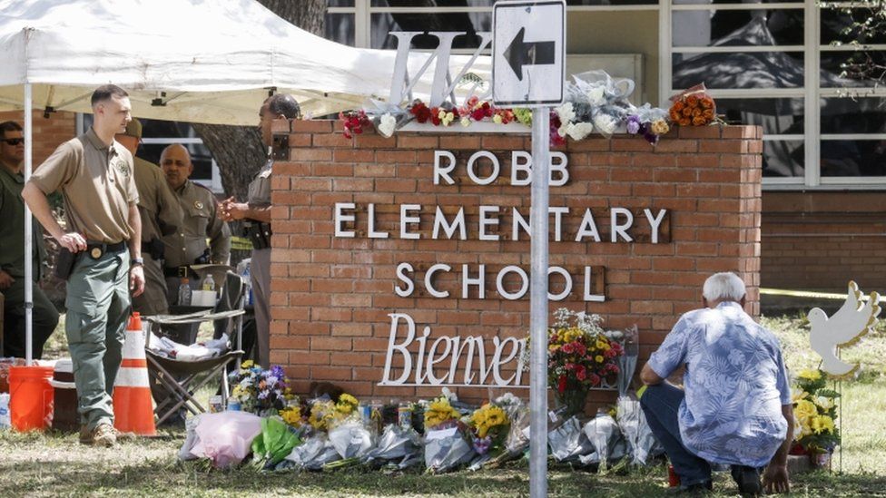 Officers stand near a memorial of flowers at the scene of the mass shooting at the Robb Elementary School in Uvalde, Texas on 25 May